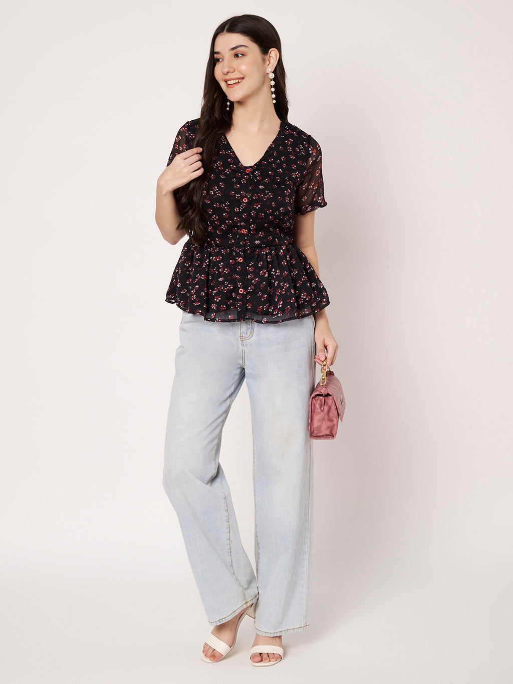 Trendy black floral peplum top styled with wide-leg denim and a pink clutch bag.