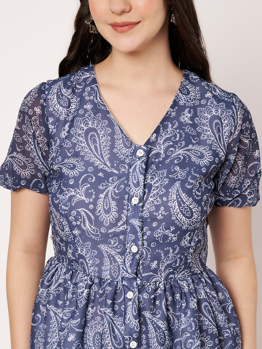 Detail shot of the button-up front and intricate white paisley pattern on a blue top.