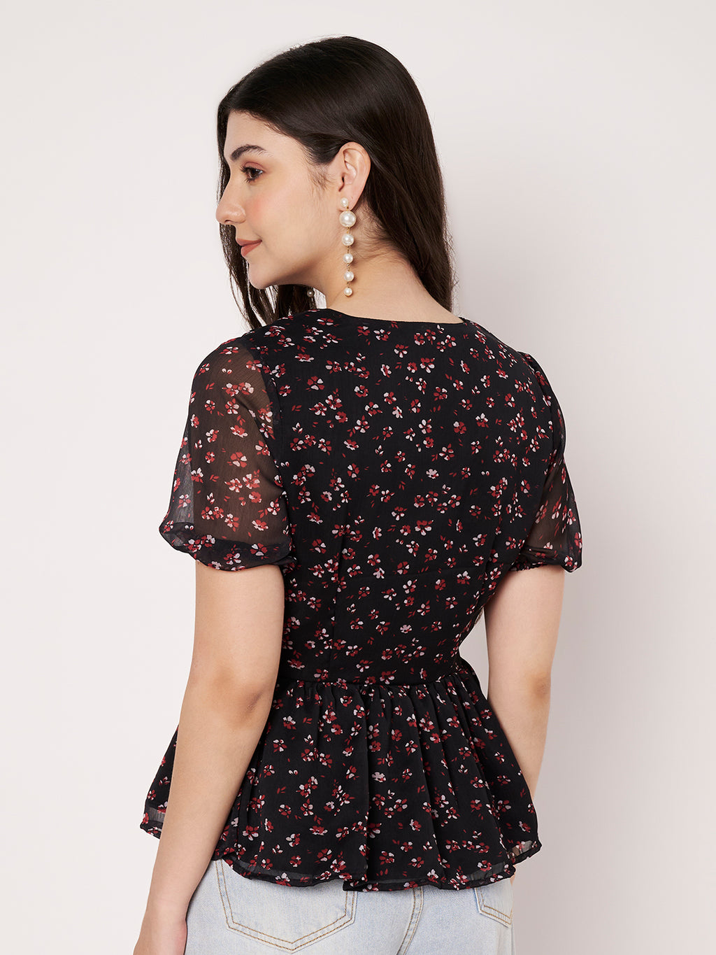 Back profile of a women's black floral print peplum top showing sleeve and waist detail.